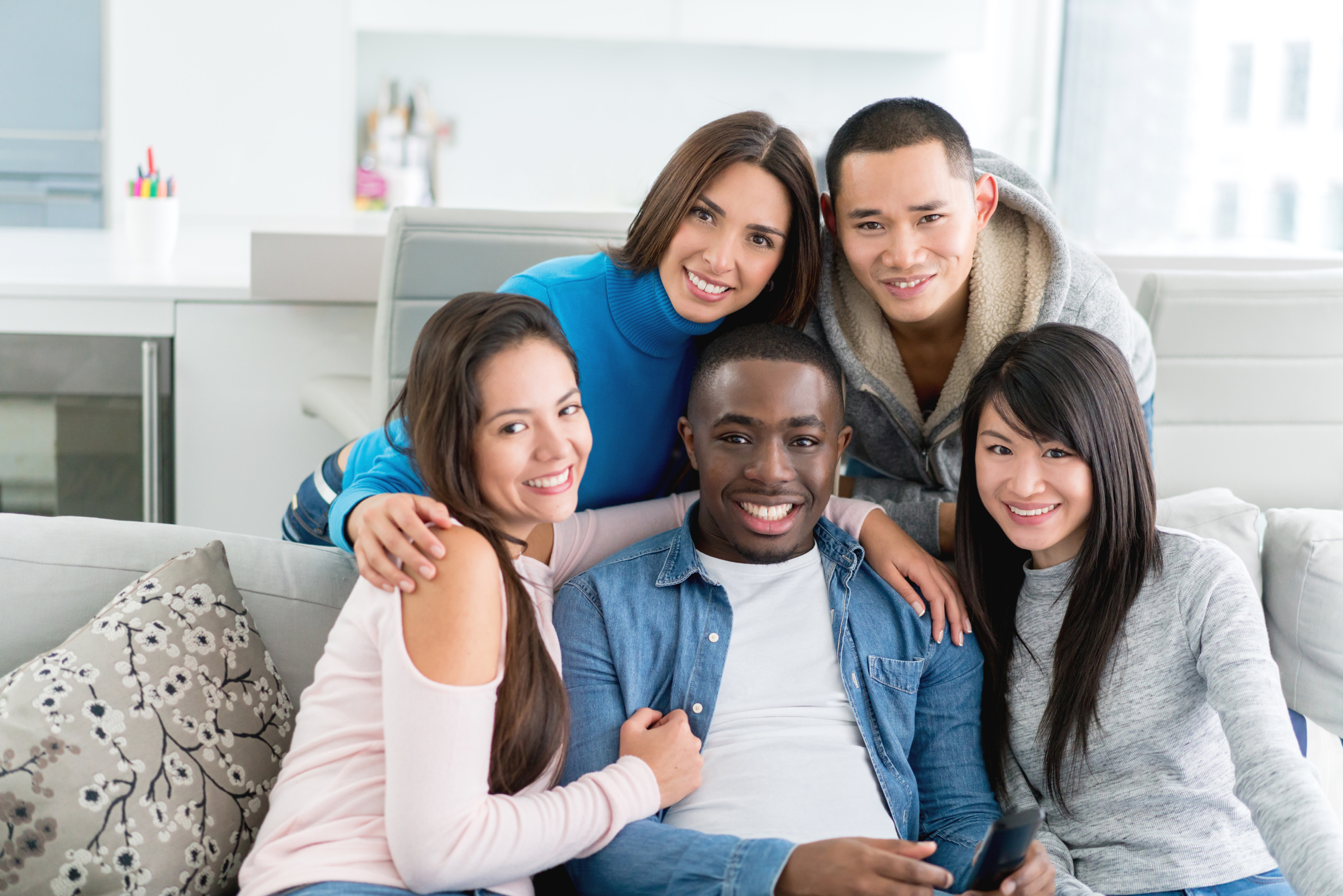 Happy group of flat mates at home looking at the camera and smiling